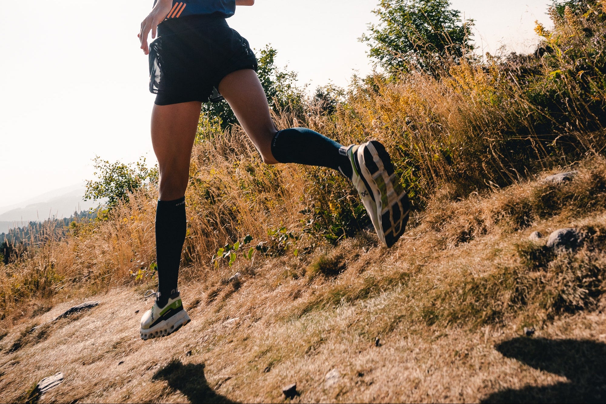 Person running on a trail with a clear blue sky